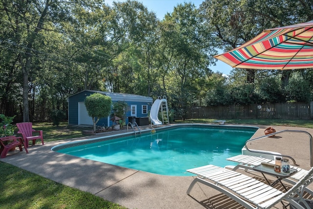 view of pool featuring an outbuilding, a water slide, and a patio area