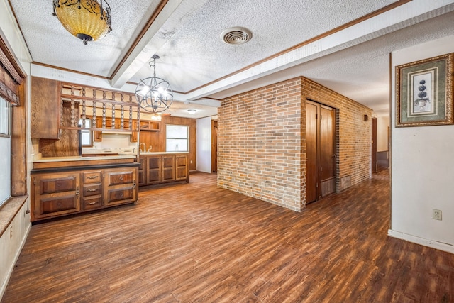 kitchen featuring beam ceiling, hanging light fixtures, dark hardwood / wood-style flooring, brick wall, and a textured ceiling