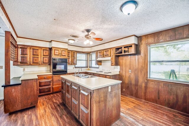 kitchen with a textured ceiling, sink, dark hardwood / wood-style floors, oven, and an island with sink