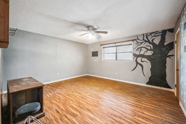 empty room featuring ceiling fan, wood-type flooring, and a textured ceiling