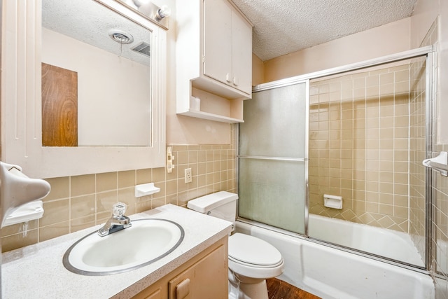 full bathroom with enclosed tub / shower combo, a textured ceiling, toilet, vanity, and tile walls