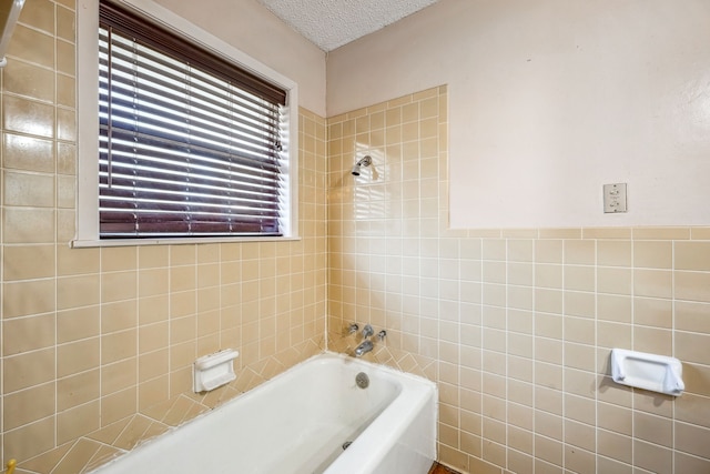 bathroom featuring a washtub, a textured ceiling, and tile walls