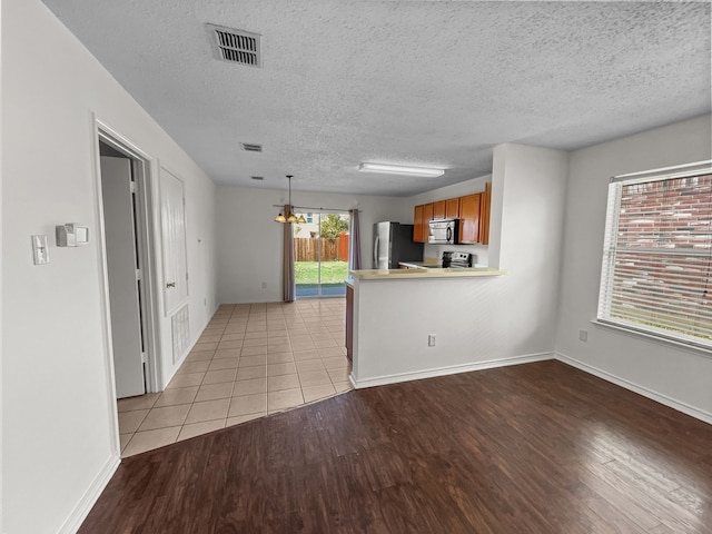 kitchen featuring a chandelier, pendant lighting, stainless steel appliances, and light wood-type flooring