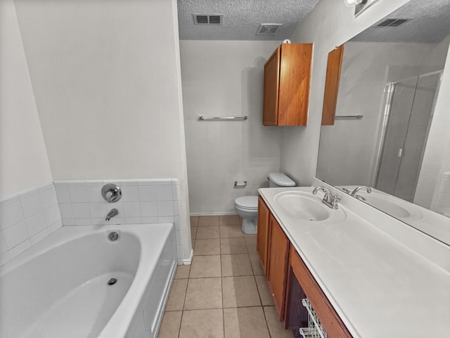 bathroom featuring tile patterned floors, a tub to relax in, a textured ceiling, toilet, and vanity