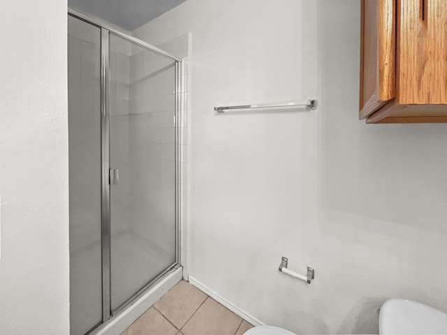 bathroom with tile patterned floors, toilet, and walk in shower