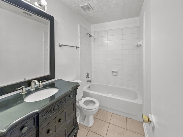 full bathroom featuring vanity, tile patterned flooring, tiled shower / bath combo, toilet, and a textured ceiling