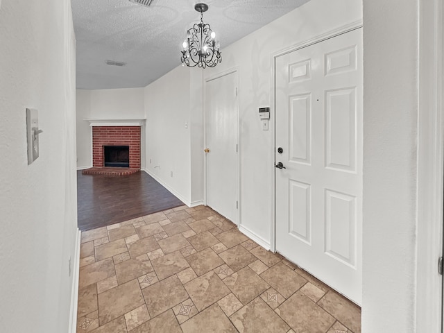 foyer entrance featuring a fireplace, a textured ceiling, and a chandelier