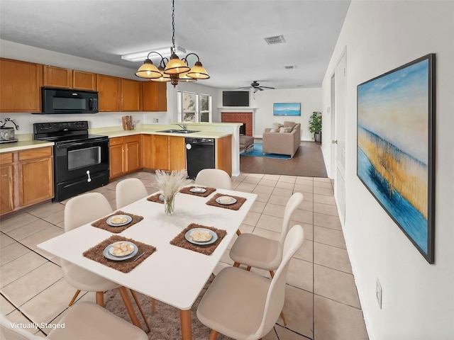 kitchen with sink, hanging light fixtures, a fireplace, light tile patterned floors, and black appliances