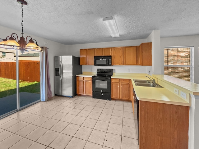 kitchen with kitchen peninsula, sink, black appliances, pendant lighting, and a chandelier