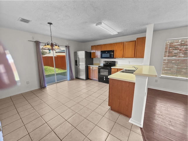 kitchen featuring black appliances, sink, decorative light fixtures, a notable chandelier, and kitchen peninsula