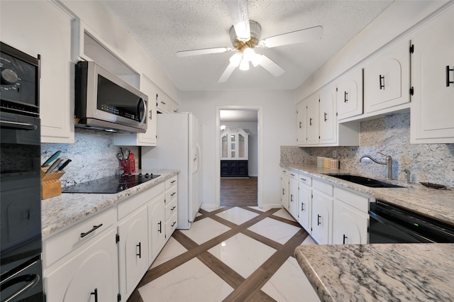 kitchen featuring sink, black appliances, a textured ceiling, light stone countertops, and white cabinets