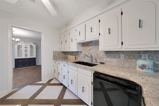 kitchen with sink, white cabinetry, black dishwasher, light stone counters, and a textured ceiling