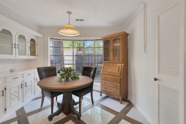 tiled dining space featuring crown molding and a textured ceiling