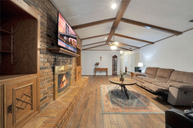 living room featuring hardwood / wood-style floors, a fireplace, lofted ceiling with beams, and a textured ceiling