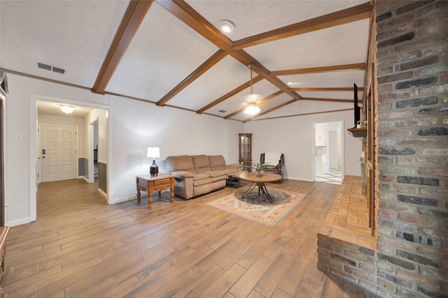 living room featuring vaulted ceiling with beams, hardwood / wood-style floors, and a textured ceiling