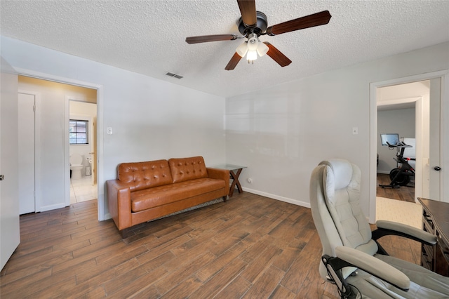 home office with ceiling fan, dark hardwood / wood-style floors, and a textured ceiling