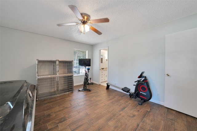 workout room with ceiling fan, dark hardwood / wood-style flooring, and a textured ceiling