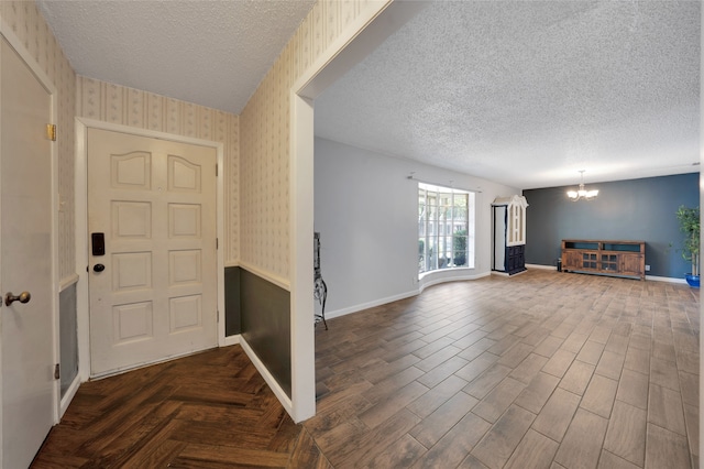 foyer entrance with dark hardwood / wood-style floors, a notable chandelier, and a textured ceiling