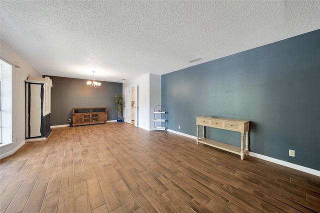 unfurnished living room featuring hardwood / wood-style floors, a notable chandelier, and a textured ceiling