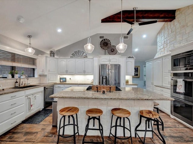 kitchen with a breakfast bar, a kitchen island, stainless steel appliances, and a sink