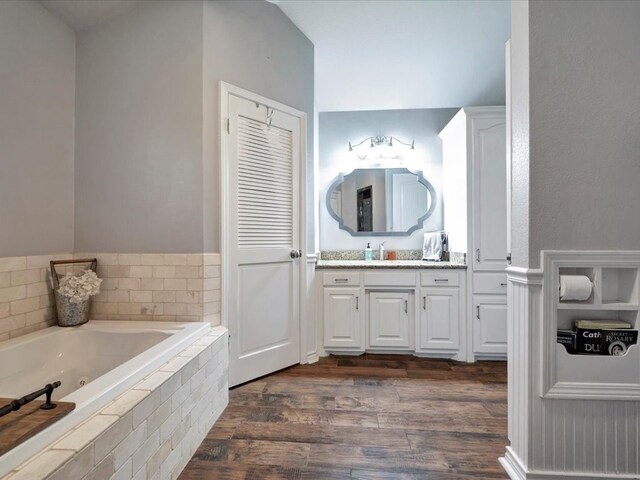 bathroom featuring a tub with jets, wood finished floors, and vanity