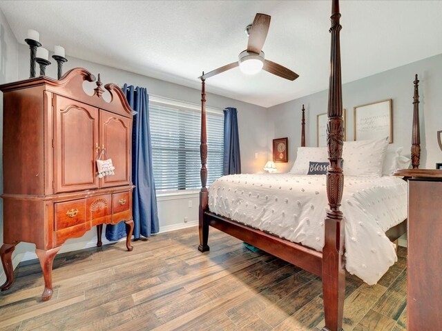 bedroom with ceiling fan, light wood-style flooring, and baseboards