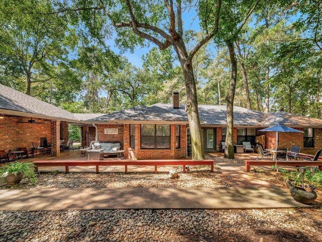 rear view of property featuring a deck, brick siding, outdoor lounge area, and a chimney