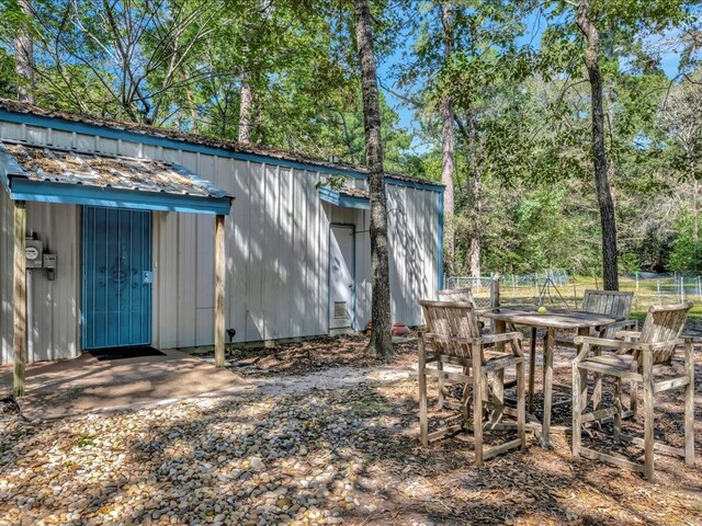 view of outbuilding with outdoor dining space, an outdoor structure, and fence