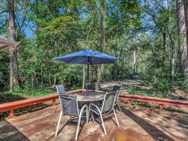 wooden deck with a forest view, outdoor dining space, and a patio area