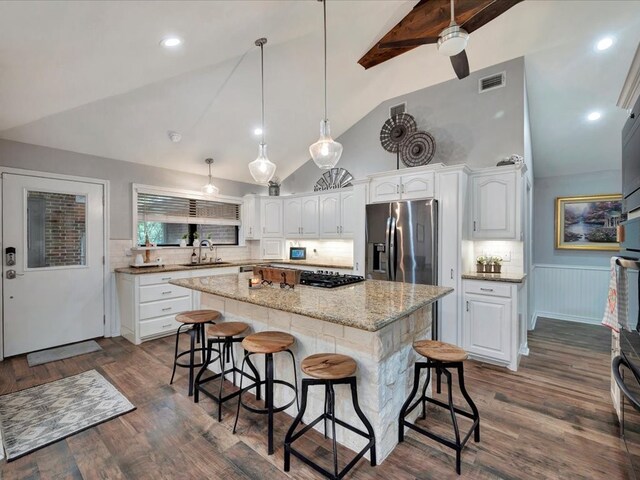 kitchen with visible vents, stainless steel refrigerator with ice dispenser, a kitchen bar, and white cabinetry