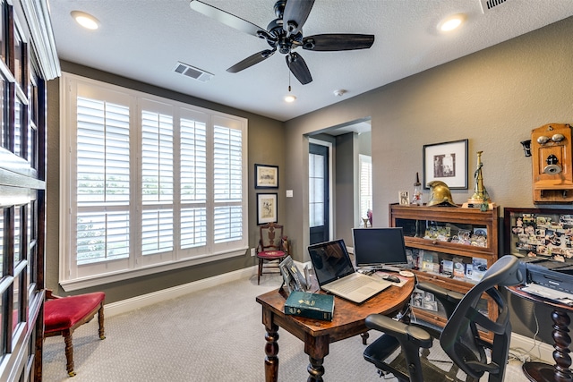 carpeted home office with ceiling fan and a textured ceiling