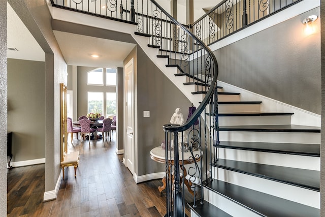 stairs featuring a high ceiling and hardwood / wood-style flooring