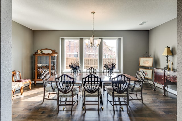 dining space with an inviting chandelier, dark hardwood / wood-style flooring, and a textured ceiling