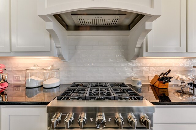 kitchen with white cabinets, stainless steel stove, and tasteful backsplash