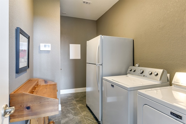 clothes washing area with washing machine and dryer and dark tile patterned floors