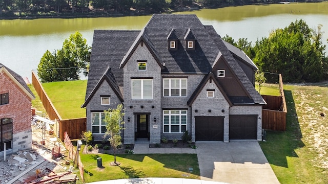 view of front of property featuring a garage, a front lawn, and a water view