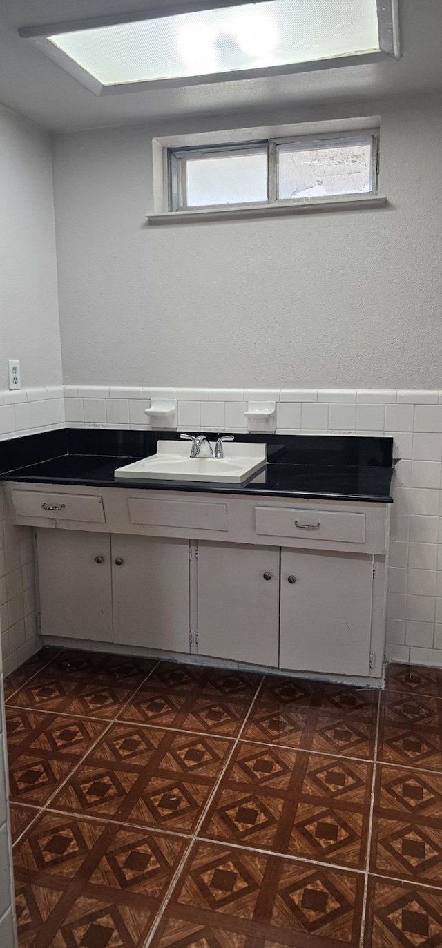 bathroom featuring tile walls, vanity, and a skylight