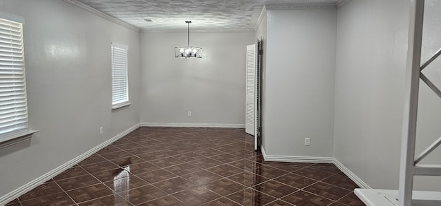 empty room with dark tile patterned floors, a chandelier, a textured ceiling, and ornamental molding