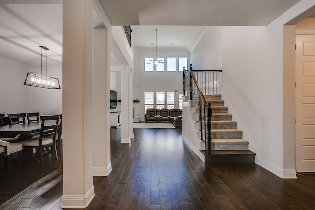 entryway with ceiling fan with notable chandelier, a high ceiling, and dark hardwood / wood-style floors