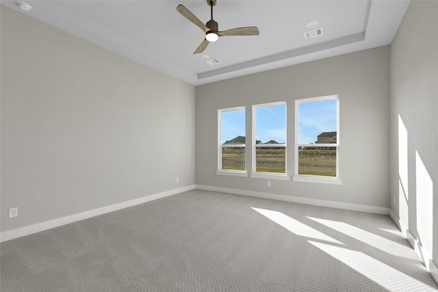 spare room featuring ceiling fan, light colored carpet, and a tray ceiling