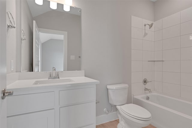 full bathroom featuring tiled shower / bath, lofted ceiling, toilet, vanity, and hardwood / wood-style flooring