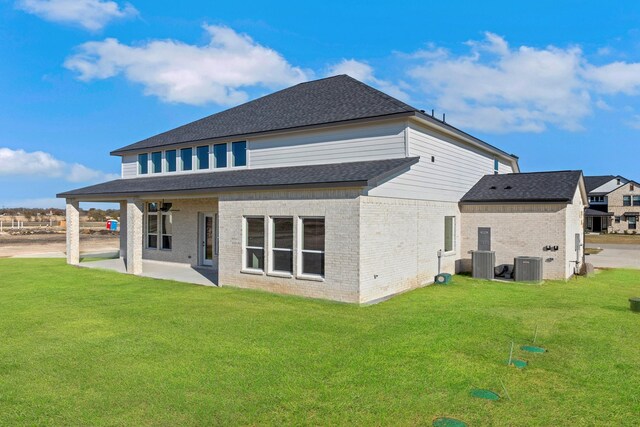 rear view of house featuring central air condition unit, a patio, and a yard