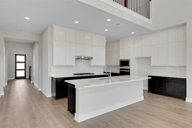 kitchen featuring appliances with stainless steel finishes, a kitchen island with sink, sink, light hardwood / wood-style floors, and white cabinetry