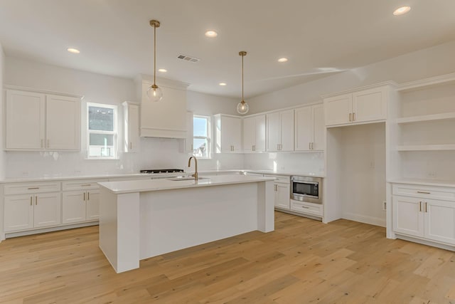 kitchen with pendant lighting, stainless steel microwave, and white cabinets