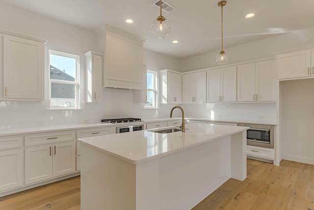 kitchen featuring decorative light fixtures, light stone countertops, sink, and white cabinets