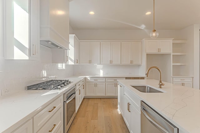 kitchen featuring sink, white cabinetry, stainless steel appliances, light stone counters, and decorative light fixtures