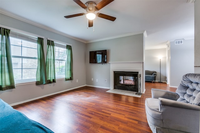 living room with wood-type flooring, a multi sided fireplace, ceiling fan, and crown molding