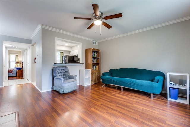 living area with ceiling fan, crown molding, and hardwood / wood-style floors