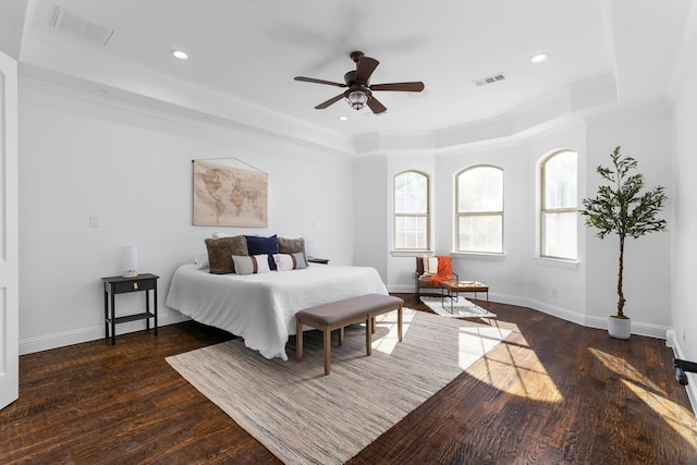 bedroom featuring dark hardwood / wood-style flooring, a tray ceiling, ornamental molding, and ceiling fan