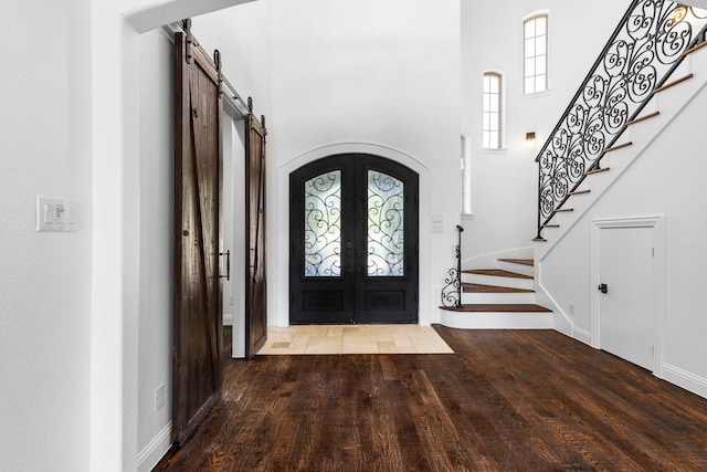 entrance foyer with hardwood / wood-style flooring, a barn door, french doors, and a high ceiling